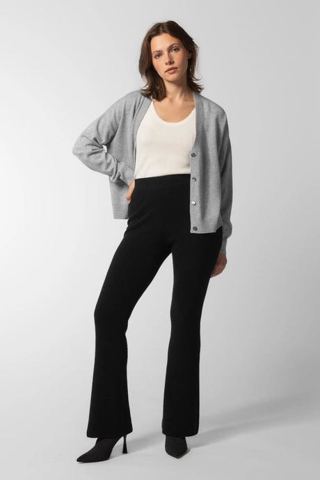 Kvinne i en myk svart  ribbestrikket slengbukse i ren kashmir til dame og en lysegrå melert kashmir-cardigan over en hvit singlet (Cashmere rib flares)